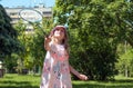 girl, European, blonde, 7-8 years old in a bright panama stands in the park and holds a badminton racket