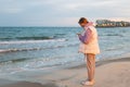 A girl of European make in casual clothes stands near the ocean with a phone in her hands is sad and looks into the Royalty Free Stock Photo