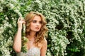 Girl in evening cocktail dress on a spring in the middle among flowering bushes and trees beautiful smiling