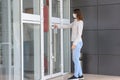 A girl in everyday clothes and a medical mask opens the door of the store