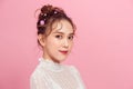 The girl with everyday makeup and hair in wedding bun with flowers on pink background