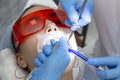 Girl on examination at dentist. treatment of carious tooth. the doctor uses a mirror on the handle and a boron machine