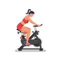 Girl on an exercise bike. A beautiful athletic girl is doing fitness.