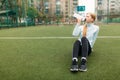 Girl after exercise, drinking water on the football field. Portrait of beautiful girl in sportswear. Royalty Free Stock Photo