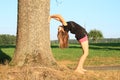 Girl exercising yoga by trunk Royalty Free Stock Photo