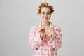 Girl is expert in beauty questions. Portrait of good-looking cozy woman in hair curlers and pyjamas with heart template