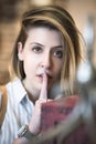 A girl with an expressive eye holds a finger near her mouth Royalty Free Stock Photo