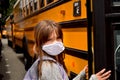 Coronavirus reopening school: wearing face mask. Girl with facemask boarding a school bus