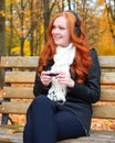 Girl in fall season listen music on audio player with headphones, sit on bench in city park, yellow trees and fallen leaves Royalty Free Stock Photo