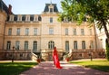 Girl fashion model in luxurious long red dress on background of an ancient European castle Royalty Free Stock Photo