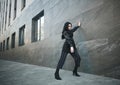 Girl in fashionable black casual clothes on background of stone wall, modern urban architecture, vogue style photo Royalty Free Stock Photo