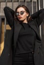 Girl in fashionable black casual youth clothes. Modern young woman in fashionable blazer in stylish black t-shirt stands on street