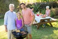 Girl, father and grandfather preparing barbecue in the park