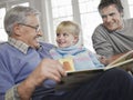 Girl With Father And Grandfather Reading Story Book