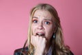 Girl in fear closes fist open mouth, curly blonde on pink background