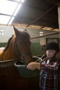 Girl feeding the horse in the stable Royalty Free Stock Photo