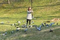 Girl feeds birds in sunny weather. Beautiful young woman feeding birds in the park at sunny fall day Royalty Free Stock Photo