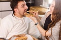 Girl feeds her husband with two slices of pizza. Exaggerate and wondering. Much credit on yourself and capabilities