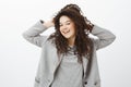 Girl feeling releived and carefree after visiting spa. Joyfull bright european female with curly hair in grey coat