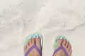 Girl feet in blue slippers on sand beach texture. Tropical seashore. Seaside banner template with text place. Royalty Free Stock Photo