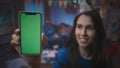 A girl in a festive hat shows a smartphone with a green screen, smiles. Close up of green screen smartphone on a blurred Royalty Free Stock Photo