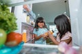 girl fighting over a bottle of sweet drink taken from the fridge