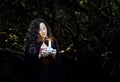 Girl finding her way by candle light in a twisted labyrinth of trees