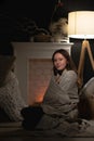 A girl by the fireplace wrapped in a blanket. Evening rest Royalty Free Stock Photo