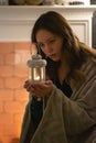 A girl by the fireplace, wrapped in a blanket, holds a candle in her hands. Evening rest Royalty Free Stock Photo