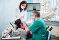 Girl with on the first dental visit. Senior pediatric dentist with nurse treating patient teeth at the dental office Royalty Free Stock Photo