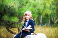 The girl is a first grader sitting at a table and holding an open book in her hands. A schoolgirl in a blue suit and curly hair Royalty Free Stock Photo