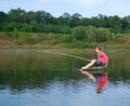 Girl-fisher sits on a log in the middle Royalty Free Stock Photo