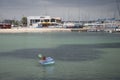 Girl fishing from an inflatable beach toy with a hoop net.