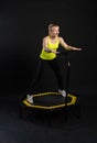 Girl on a fitness trampoline on a black background in a yellow t-shirt yellow fit jump, equipment health vitality, club Royalty Free Stock Photo