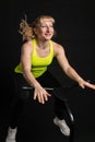 Girl on a fitness trampoline on a black background in a yellow t-shirt black jump, equipment caucasian health movement Royalty Free Stock Photo