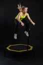 Girl on a fitness trampoline on a black background in a yellow t-shirt yellow energy jump, active exercise athlete girl Royalty Free Stock Photo