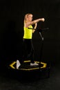 Girl on a fitness trampoline on a black background in a yellow t-shirt trampoline gym sport, equipment female healthy Royalty Free Stock Photo