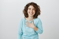 Girl is flatter to bottom of heart. Studio shot of pleased and thankful beautiful caucasian female, holding palm on