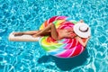 Girl floats on a lollipop shaped float over blue swimming pool water Royalty Free Stock Photo