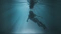 A girl floats to the surface under water against a background of sunshine