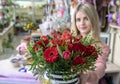 A girl, a florist-designer holds out a beautiful, festive bouquet of red flowers and a heart with the inscription love, specially Royalty Free Stock Photo