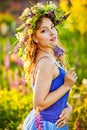 A girl with a flower wreath on her head sits at sunset in a field with purple lupin flowers. Image with selective focus  toning Royalty Free Stock Photo