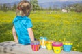 Girl on flowering field with colorful painted garden pots
