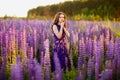 Girl with flowers lupines in a field at sunset