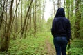 Girl with flowers on a path in the forest. The grass is green near tall slender trees. Young trees stately row. In the middle