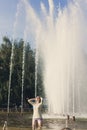 Girl with flowing hair in short shorts and sunglasses is standing in the fountain