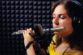 Girl flute player plays in music studio, copy space. Record wind musical instruments with a professional microphone. Woman in
