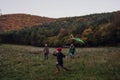 Girl flying kite on meadow, running, having fun with parents. Autumn windy weather for kite flying. Royalty Free Stock Photo