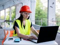 Girl foreman with laptop at construction site. Female engineer works on a computer on the background of a building under Royalty Free Stock Photo