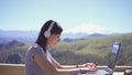 Girl is a freelancer blogger in headphones with laptop on the nature